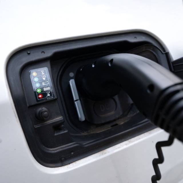 Der Stecker einer Ladesäule ist beim Ladevorgang an einem Auto zu sehen.