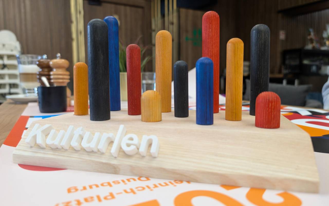 Eine Holzplatte mit bunten Stäben in verschiedenen Farben, die herausragen. So sieht der DU-Kulturen-Award aus.