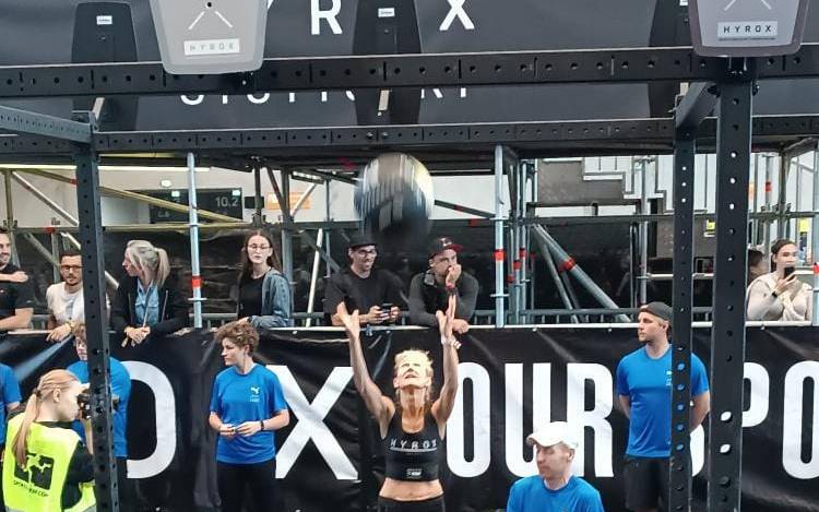 Anette Meier-Ullmann aus Duisburg wirft einen Medizinball auf einem Hyrox-Wettkampf in die Höhe.