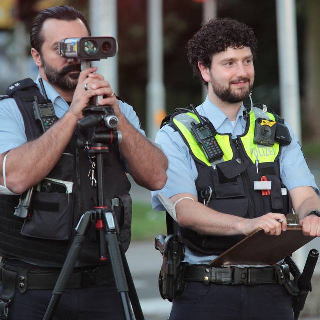 Zwei Polizisten kontrollieren Fahrzeuge mit einem Radar-Gerät.