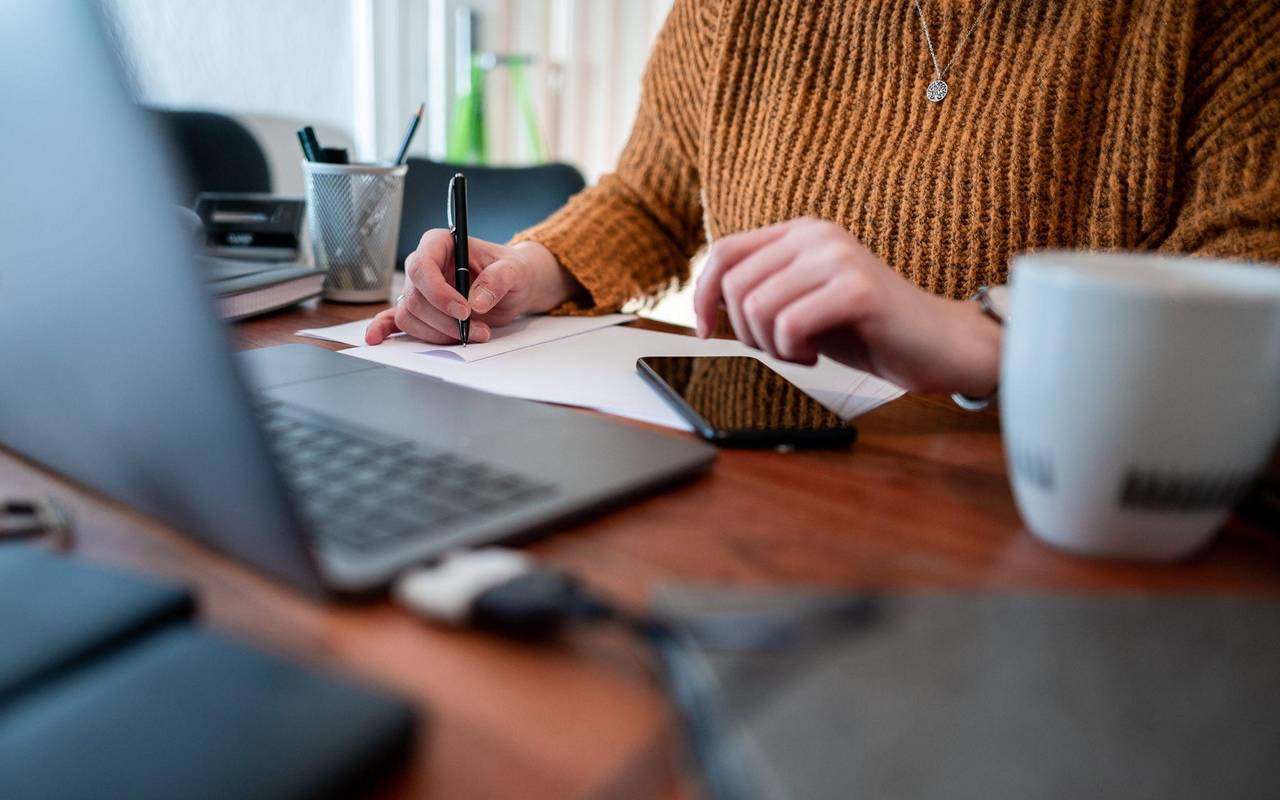 Frau sitzt mit einem Laptop am Tisch