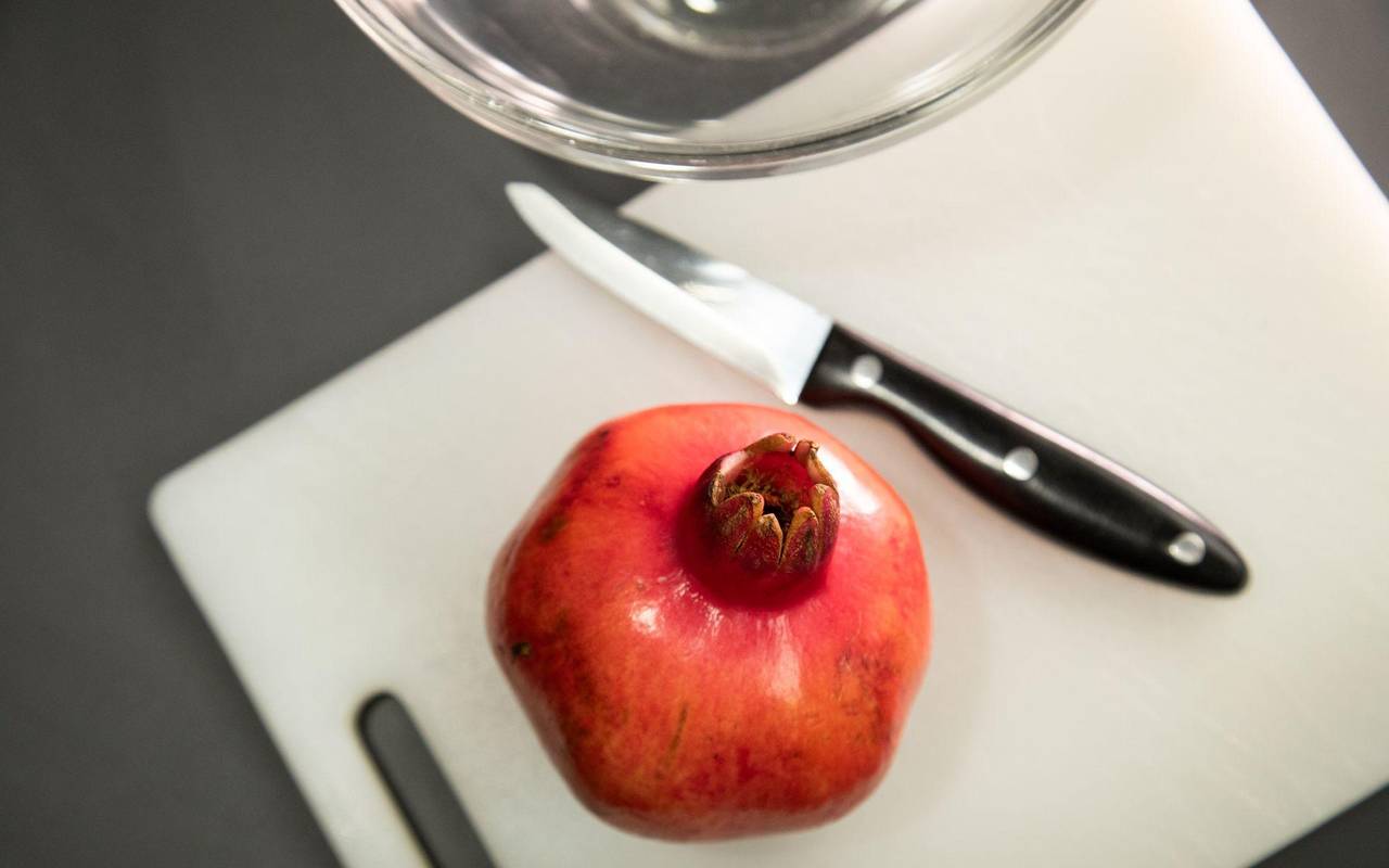 Granatapfel liegt neben einem Messer auf einem Tisch