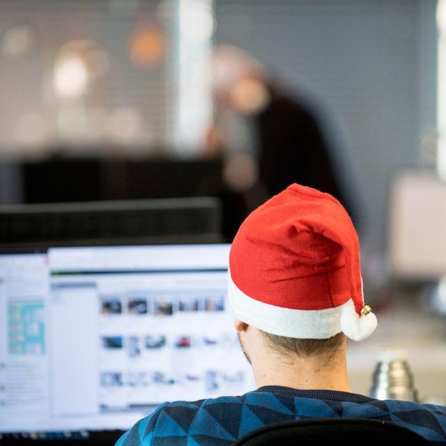 Ein Mann sitzt mit Weihnachtsmütze im Büro