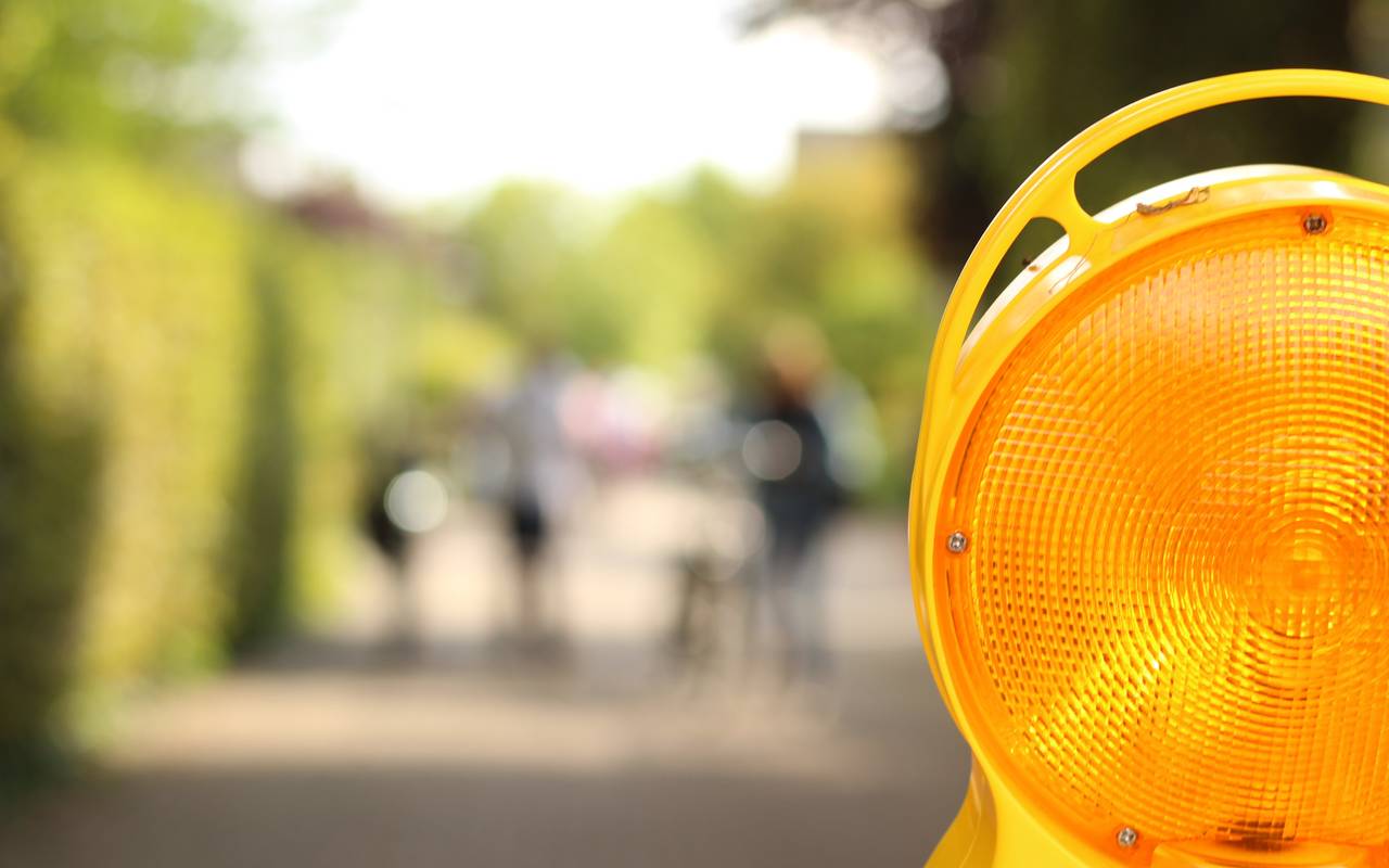 Eine Nahaufnahme einer gelb blinkenden Warnleuchte im Straßenverkehr, die zum Beispiel bei Sperrungen verwendet wird.