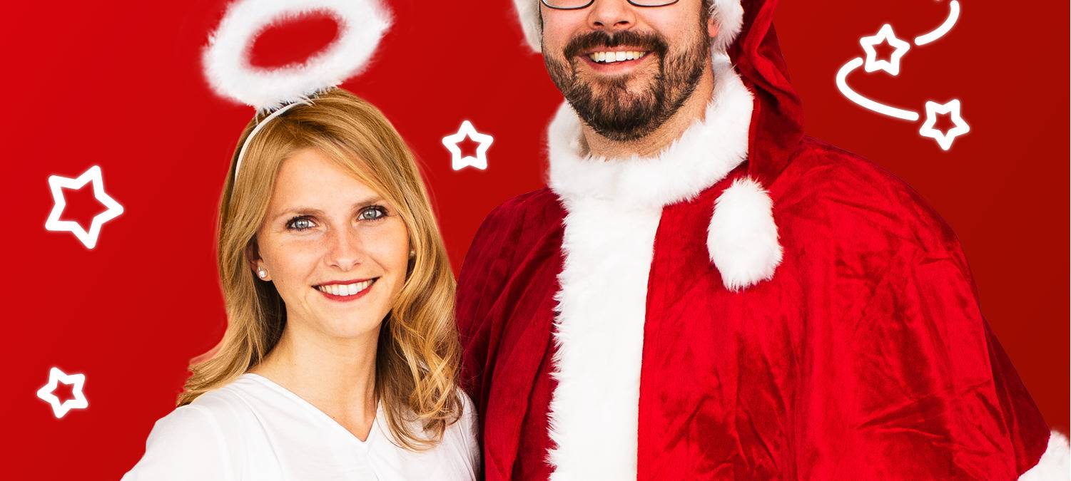 Olli & Jana stehen weihnachtlich im Weihnachtsmann- und Engelskostüm vor der Kamera.
