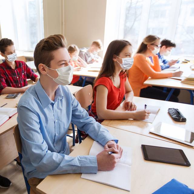 Schüler sitzen im Klassenraum und tragen einen Mundschutz.