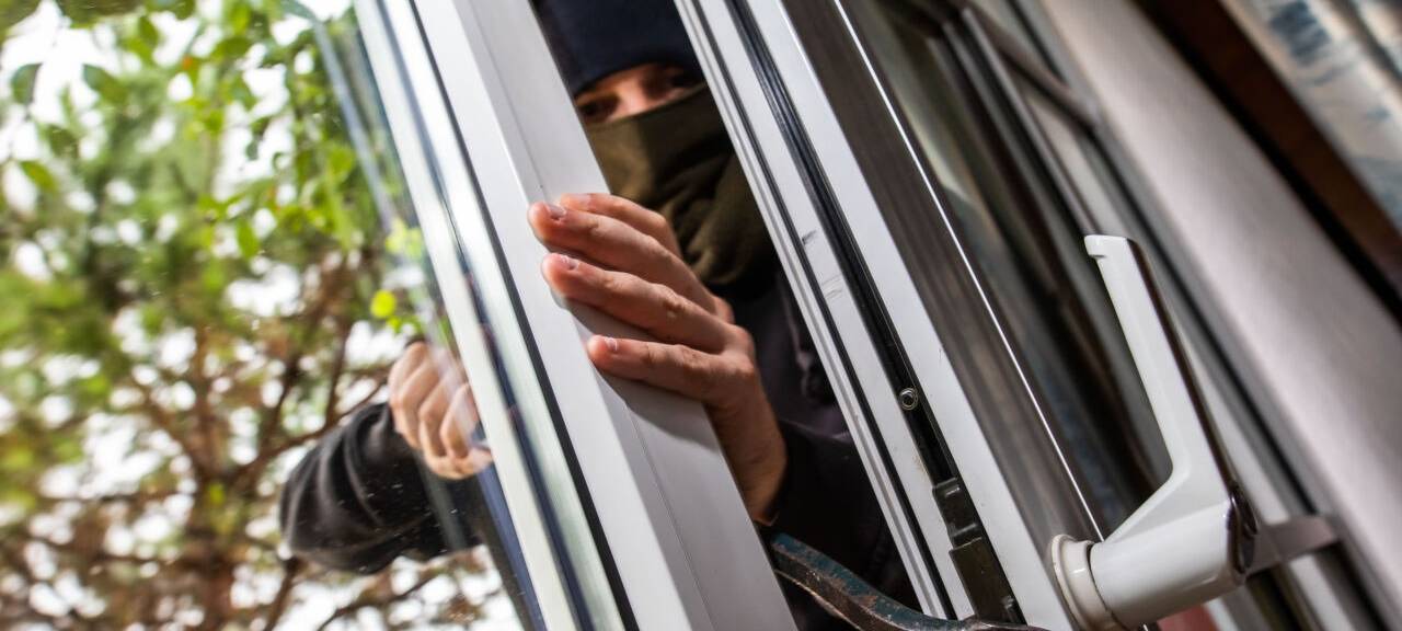 ILLUSTRATION - Ein Mann mimt einen Einbrecher und benutzt ein Brecheisen, um eine gekippte Terrassentür aufzuhebeln. Maßnahmen für privaten Einbruchschutz sollten nach Auffassung der SPD auch in Zukunft vom Land finanziell unterstützt werden. (zu dpa "SPD kritisiert Streichung der Mittel für privaten Einbruchschutz")