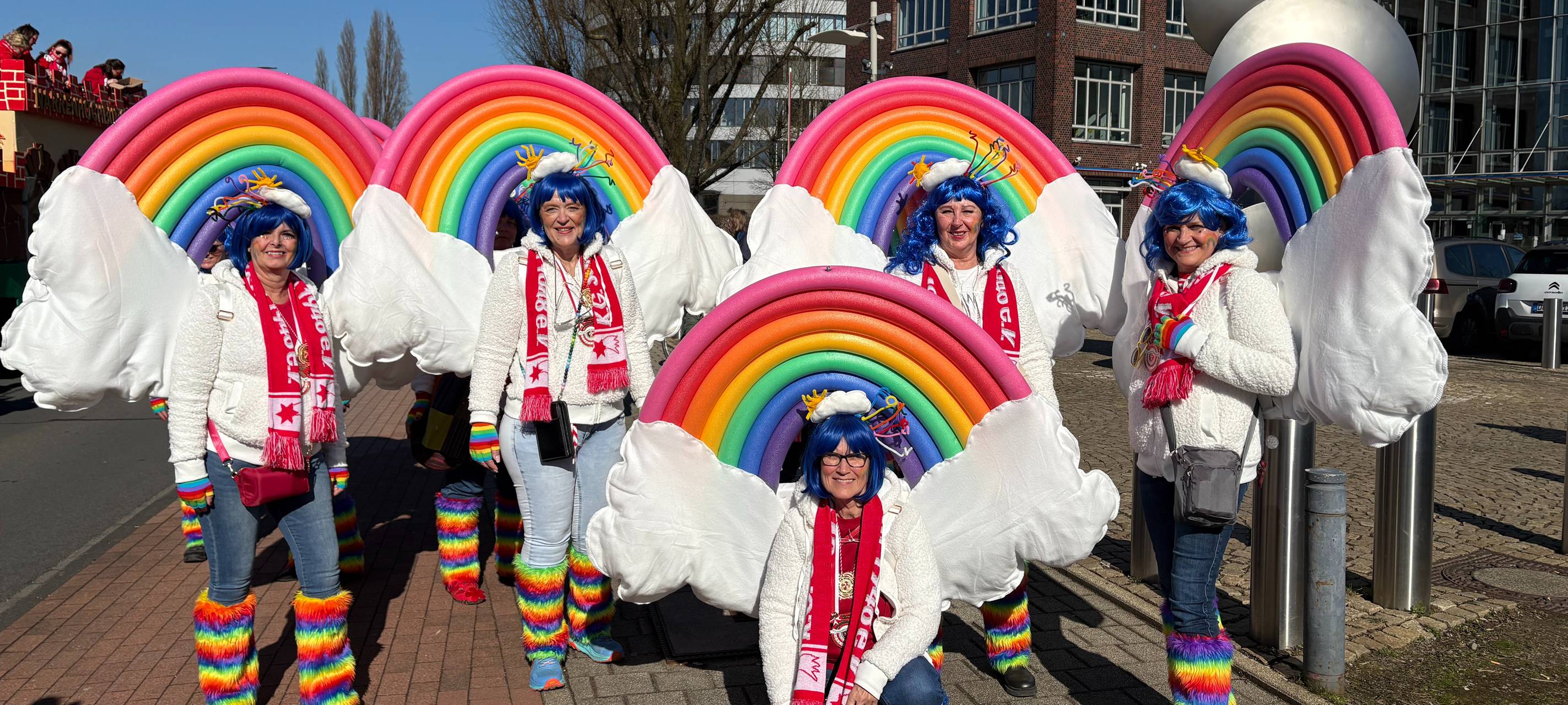 Duisburger Karnevalisten im Regenbogenkostüm gehen zum Rosenmontagsumzug.