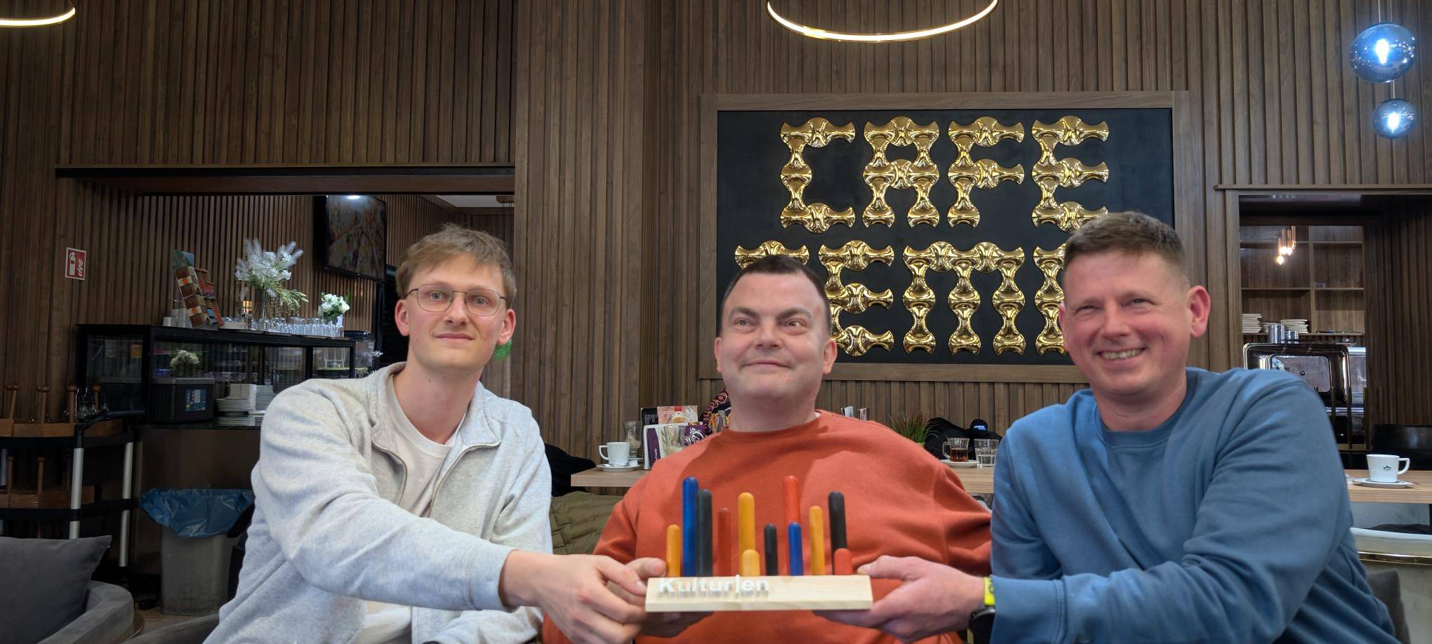 Teamleiter Marc Pfaffl, Mitarbeiter Robin Tiemann und Geschäftsführer Dirk Suceska zeigen die Trophäe.