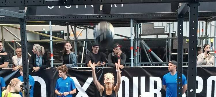 Anette Meier-Ullmann aus Duisburg wirft einen Medizinball auf einem Hyrox-Wettkampf in die Höhe.