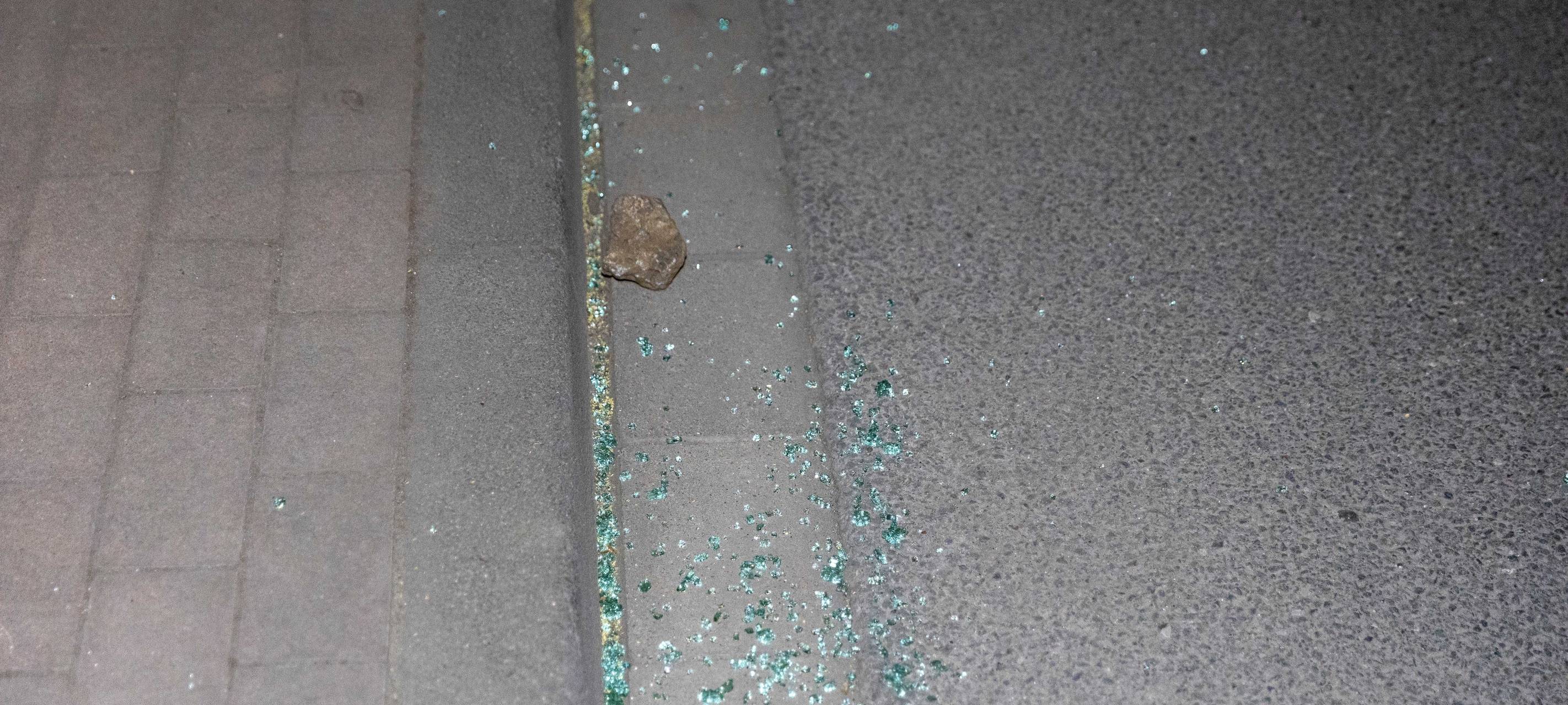Stein liegt mit Glasscherben auf der Straße.