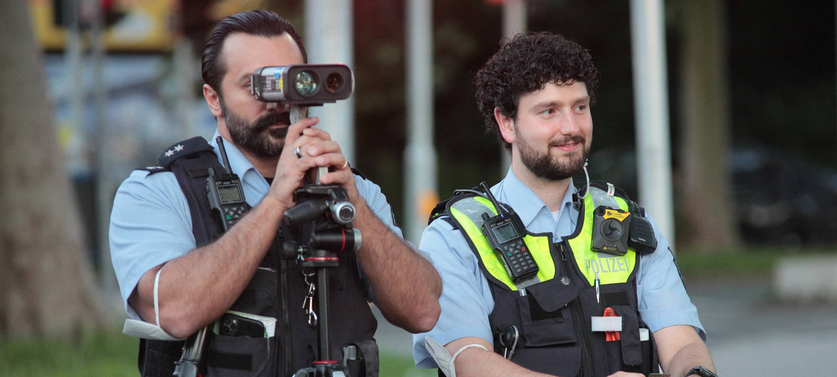Zwei Polizisten kontrollieren Fahrzeuge mit einem Radar-Gerät.