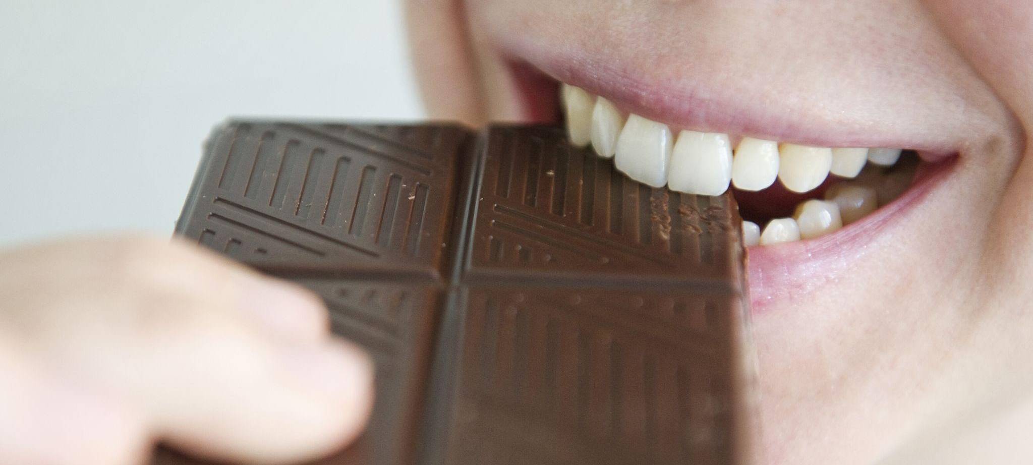 Frau beißt in ein Stück Schokolade