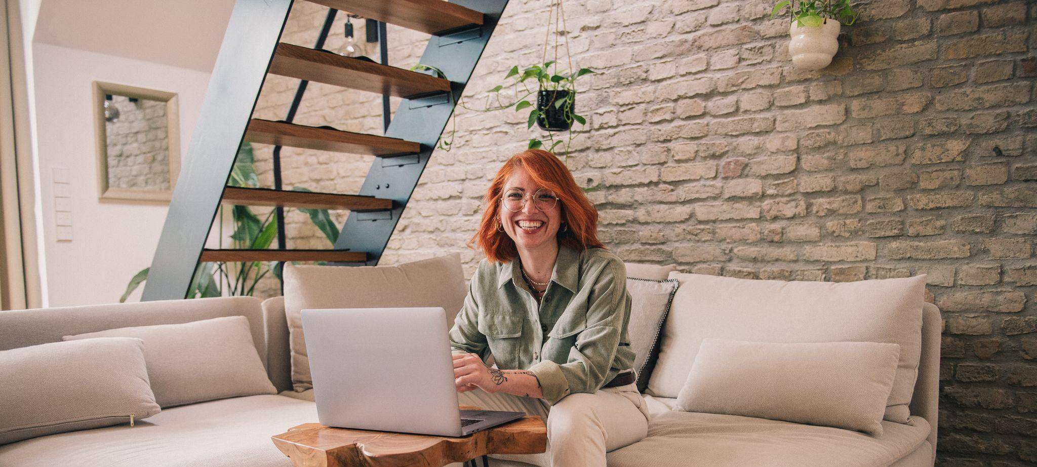 Eine Frau am Laptop sitzt auf einem Sofa