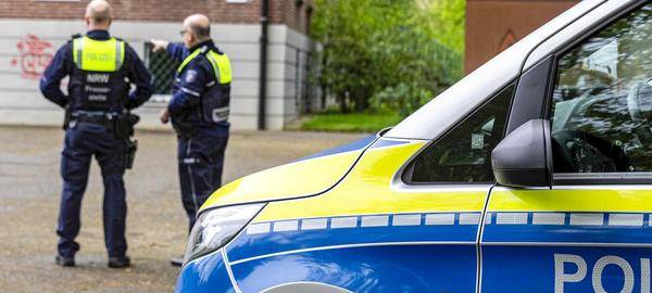 Zwei Polizisten unterhalten sich vor ihrem Dienstwagen.