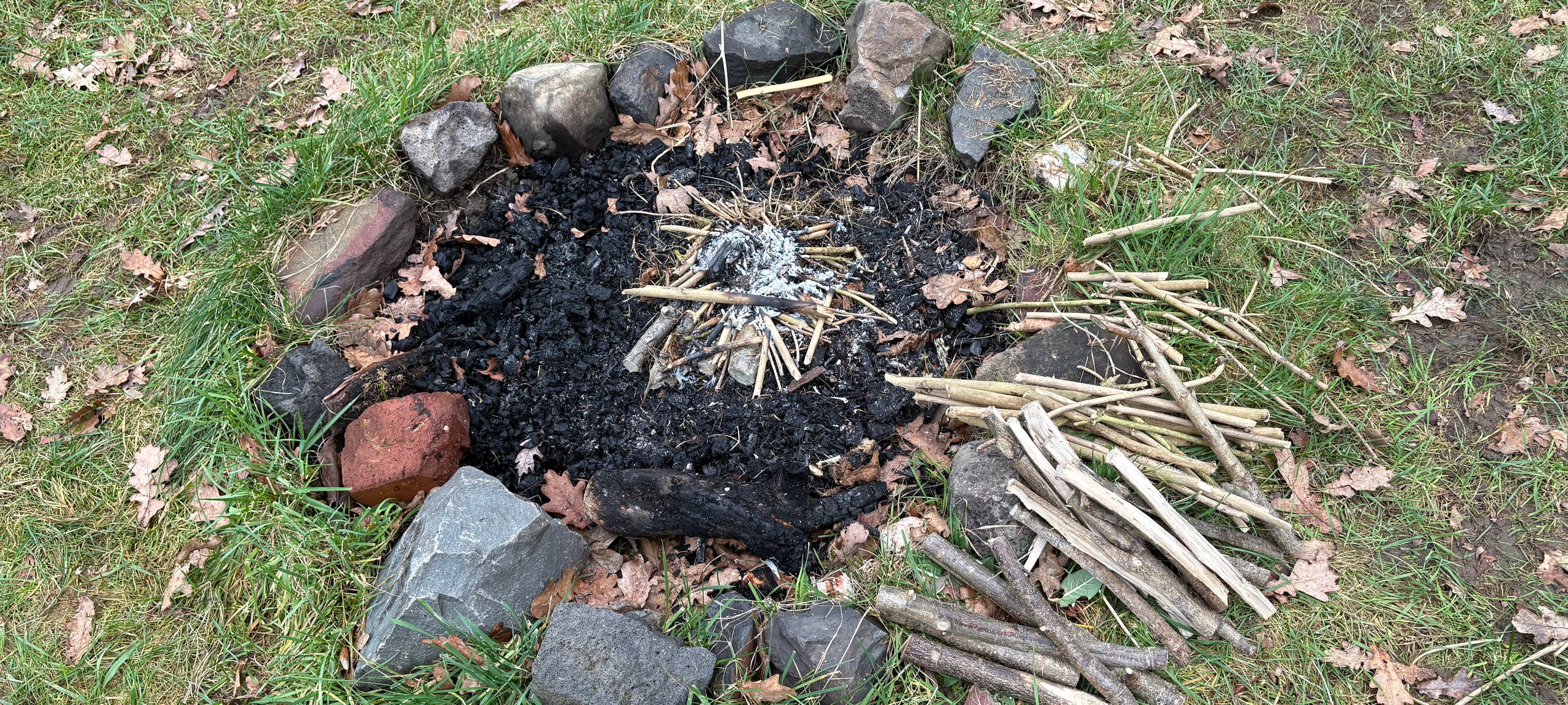 An seiner Feuerstelle übt Christian Elberg regelmäßig das Feuer machen mit einem Drillbogen.