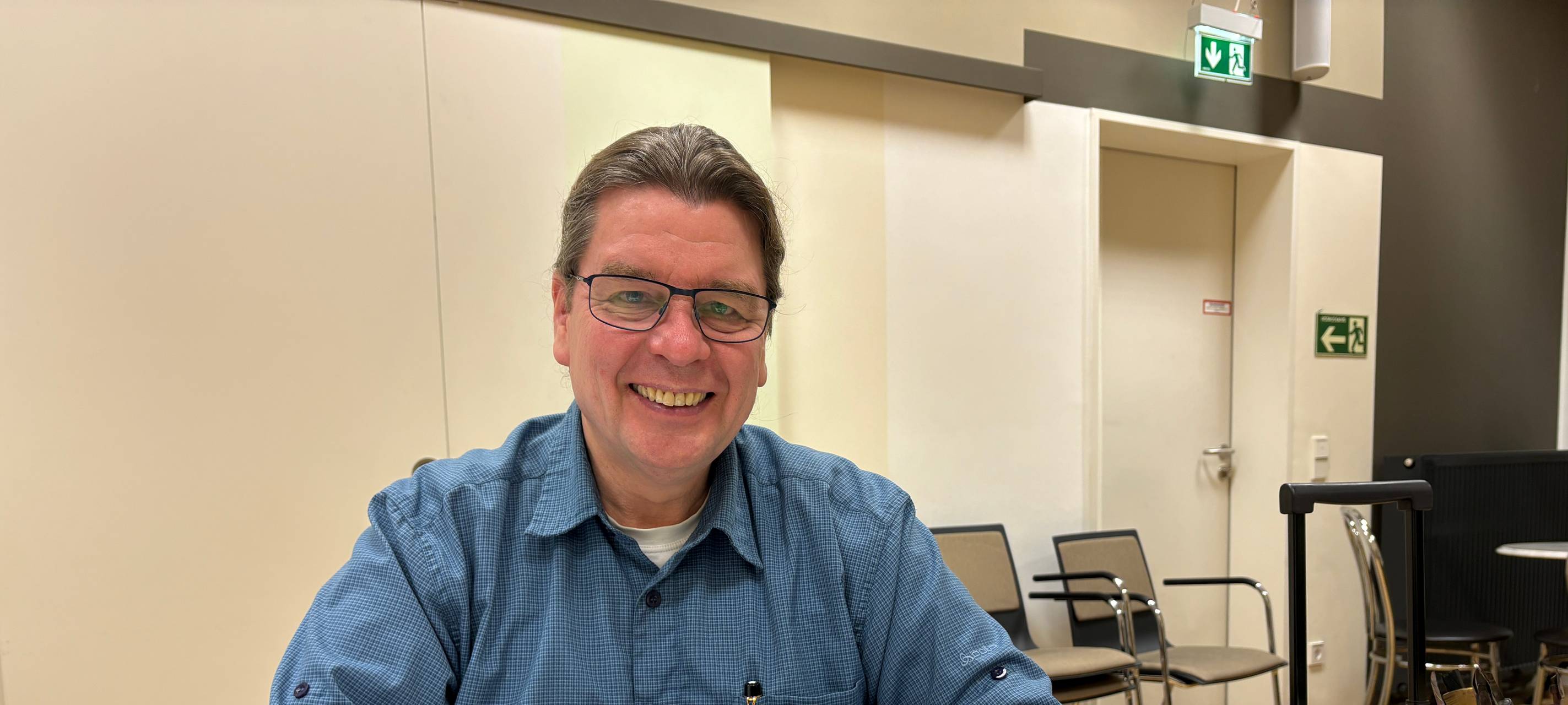 Udo Schwidder an einem Tisch, vor ihm ein Tintenfass und Papier und Stift.