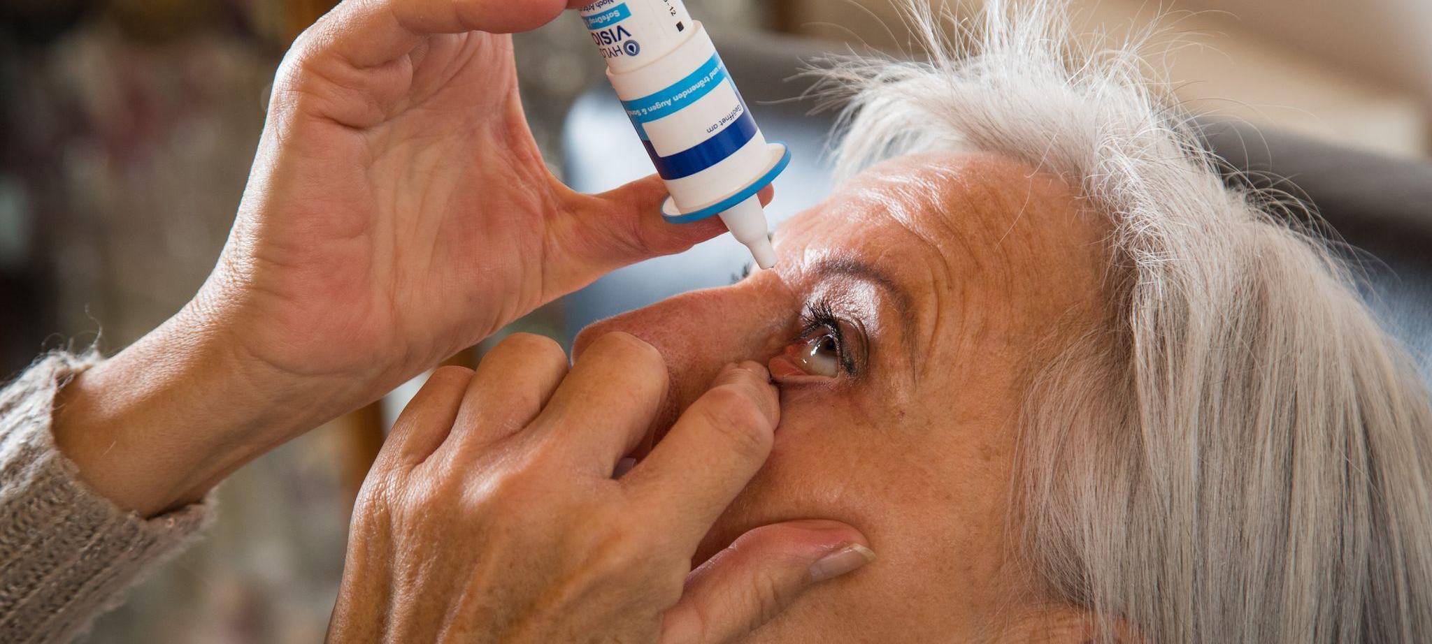 Eine Seniorin benutzt Augentropfen
