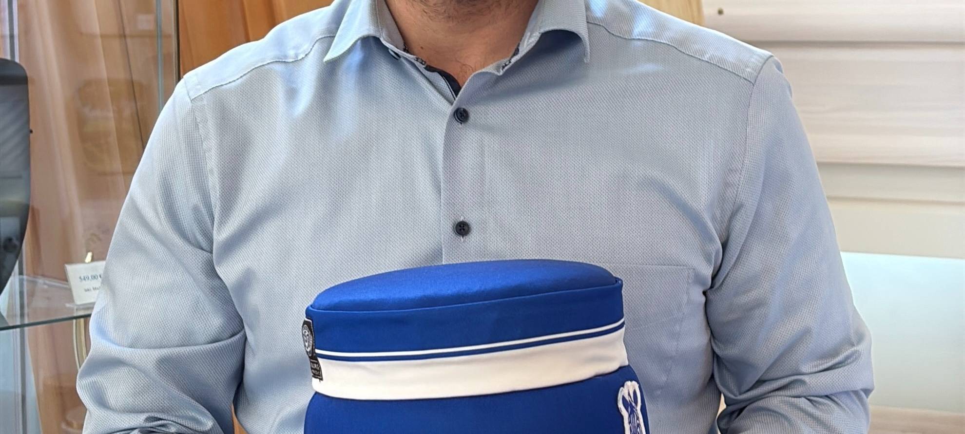 Ulrich Kretschmer hält eine Urne aus einem MSV-Trikot hoch.