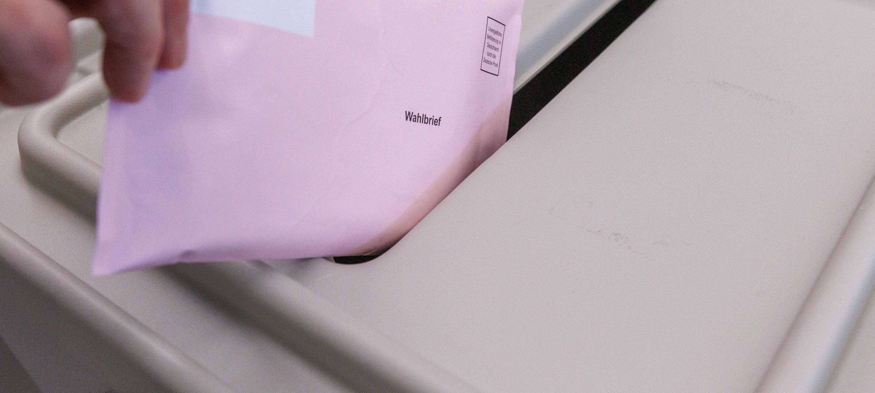 Ein Wahlzettel wird in die Urne eingeworfen.