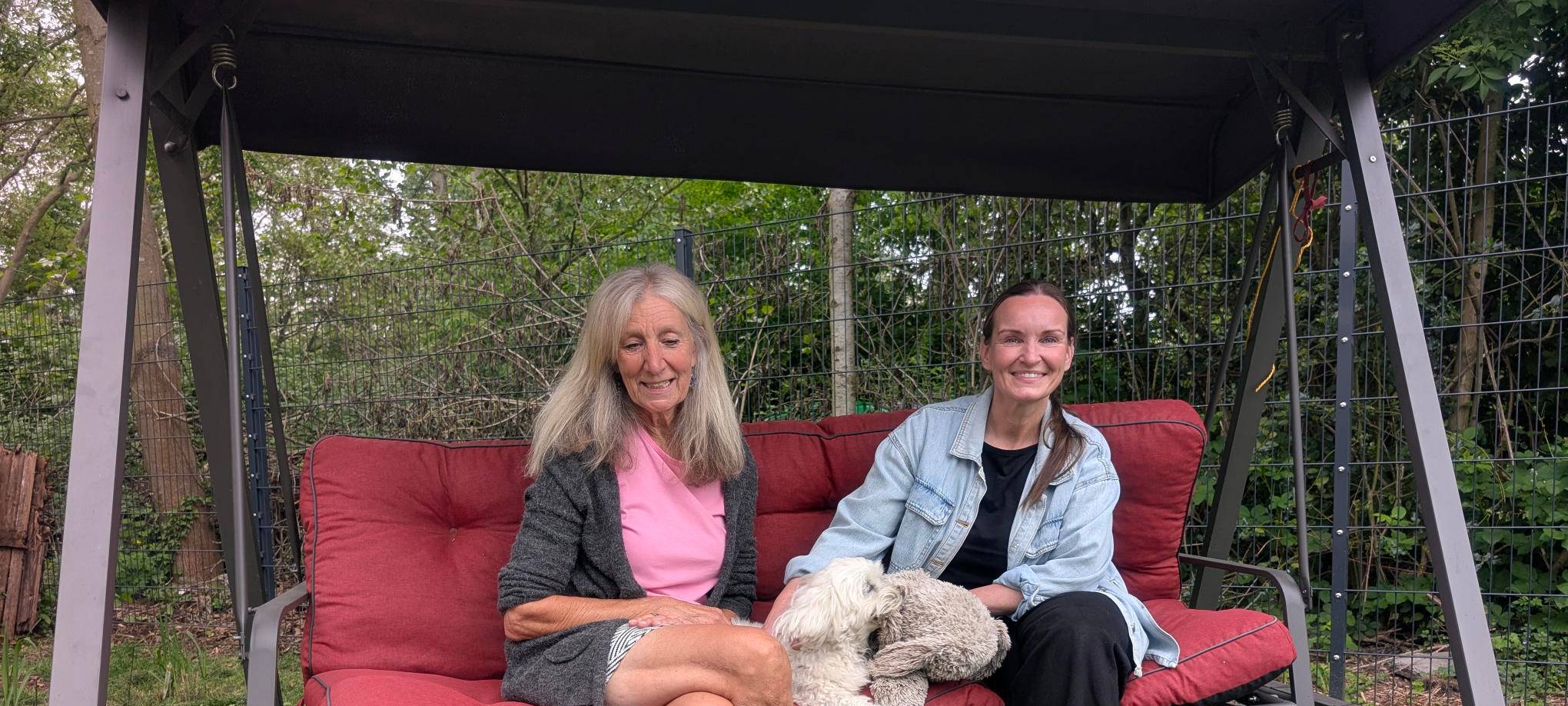 Die beiden Frauen Sabine Dürfeld und Nadine Hoika möchten im Ruhrgebiet das Projekt "Silberfoten" etablieren, das ehrenamtliche an Senioren vermittelt, die Unterstützung mit Haustieren brauchen. Hier sitzen sie gemeinsamen mit den Hunden Maya, Lucky Luke und Sammyin einer Gartenschaukel.