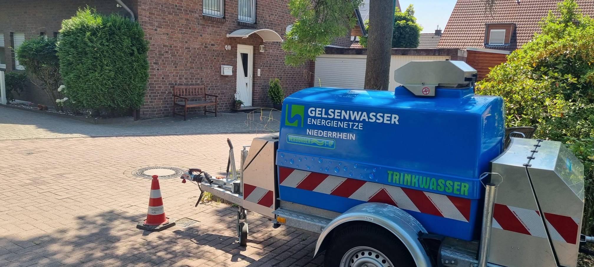 Ein blauer Anhänger liefert Trinkwasser in Huckingen.