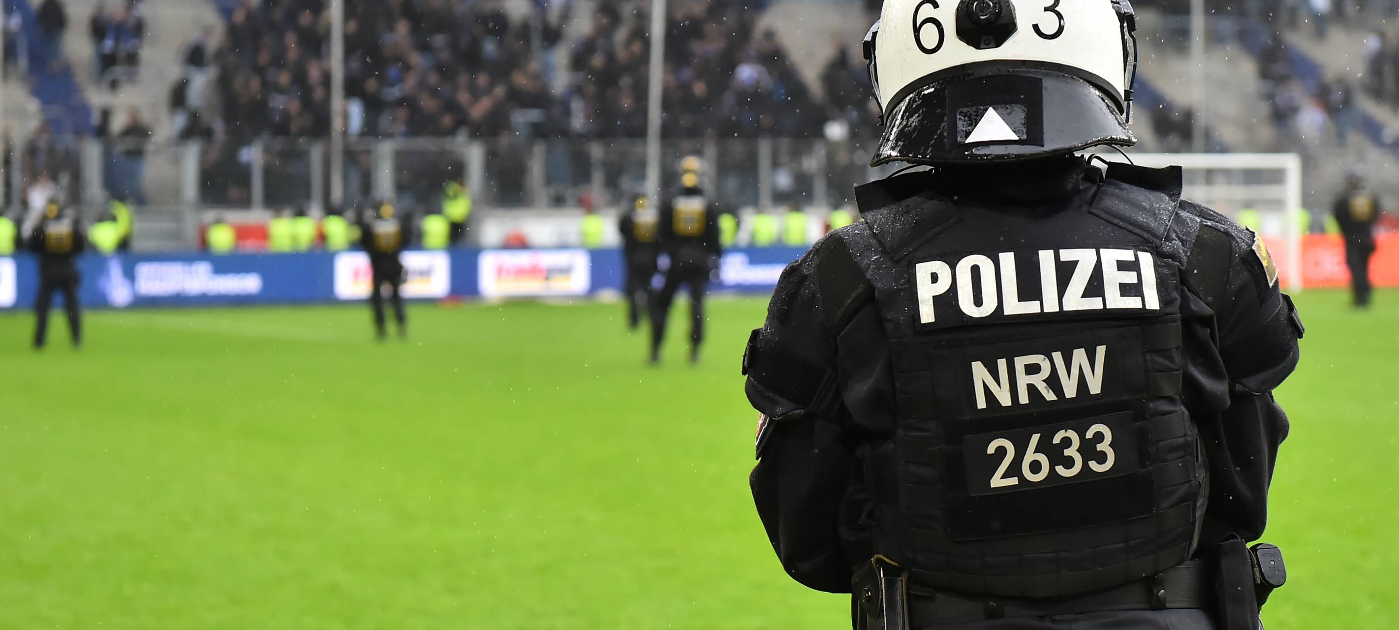 Ein Polizist steht mit dem Rücken zur Kamera vor der Fankurve des MSV Duisburg.