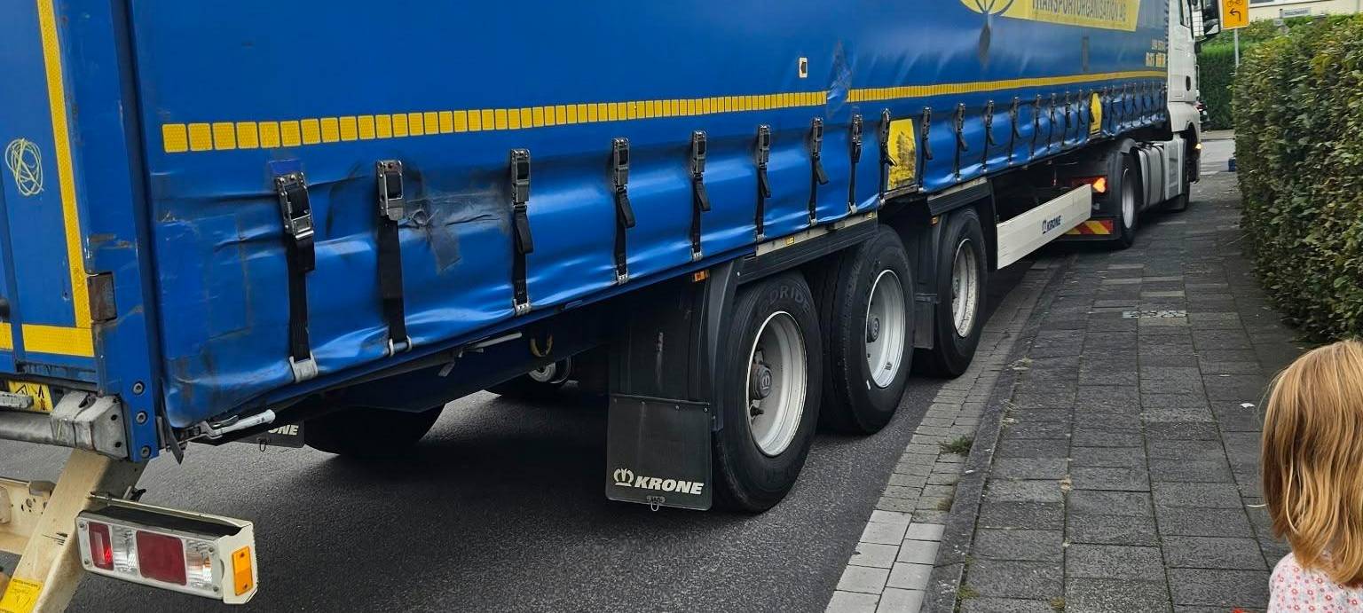 Ein Kind steht vor einem LKW, der über den Bordstein in Duisburg-Rheinhausen in eine Straße abbiegt.
