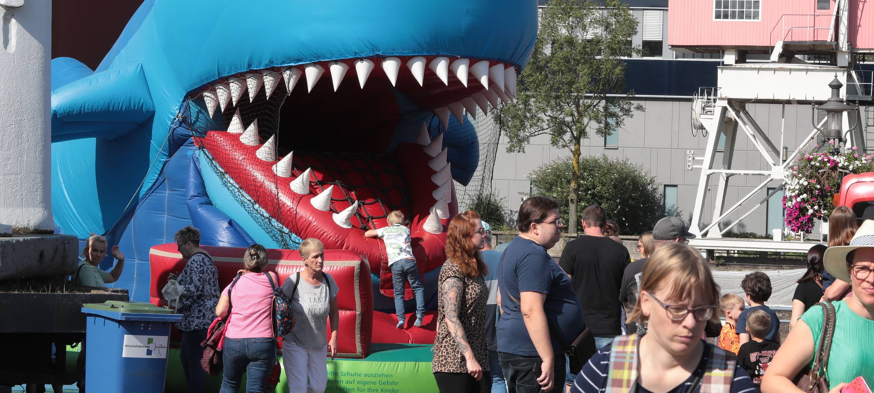 Eine große Hüpfburg, die aussieht wie ein Hai, bei dem Kinder zum Mund reinklettern und dann zur Flosse wieder rauskommen, ist ein Highlight beim Weltkindertag im Duisburger Innenhafen.